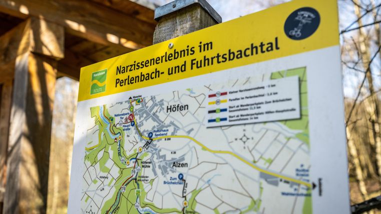 A signpost with a map of the daffodil experience in the Perlenbach and Fuhrtbachtal. The map shows various paths and places in the surrounding area.