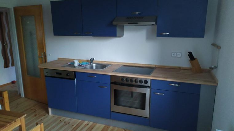 A modern kitchen with blue cabinets and a wood countertop. The equipment includes a stove, an oven, and a sink.