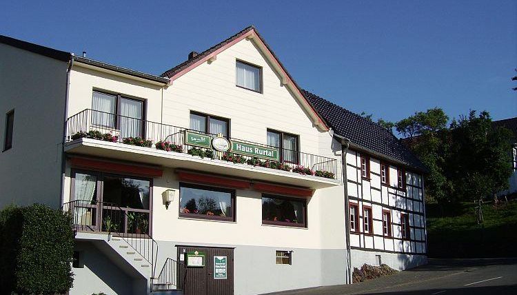 A charming building with a landscaped entrance area. The facade is friendly and inviting, with flowers on the balcony.