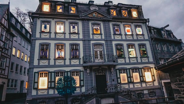 A historic building with colorful windows and a beautiful facade. The evening sky is gray and gives the scene a calm atmosphere.