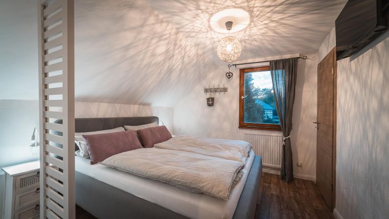 Een moderne slaapkamer met een groot bed en gezellige beddengoed. Het raam laat natuurlijk licht binnen en creëert een uitnodigende sfeer.