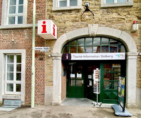 An entrance area of Stolberg Tourism with a large sign. Next to the entrance stands an additional sign with information for visitors.