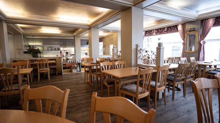 Ein gemütliches Restaurant mit Holztischen und Stühlen. Die Räume sind hell und einladend gestaltet.