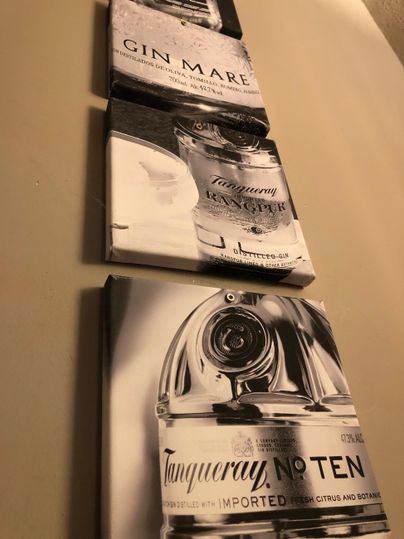 A wall mural featuring three graphics of gin bottles. The bottles are depicted in black and white and showcase the brands Gin Mare and Tanqueray No. Ten.
