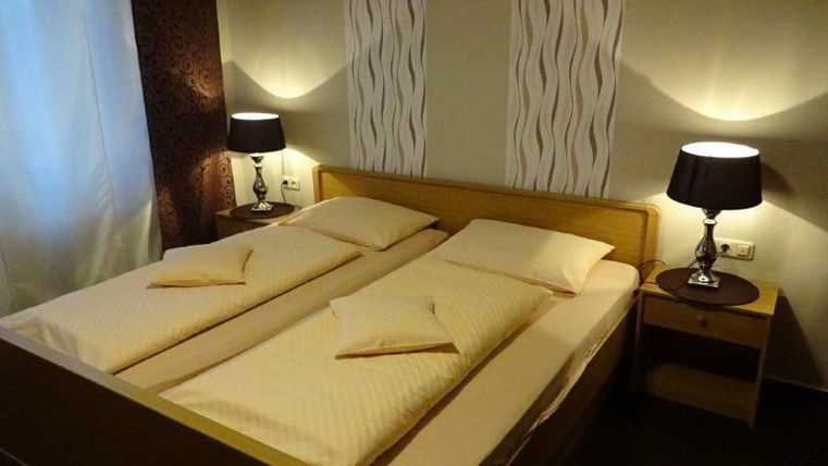 Een gezellige slaapkamer met een tweepersoonsbed en twee nachtkastjes. De muren zijn in zachte kleuren gehouden, en zacht licht creëert een uitnodigende sfeer.