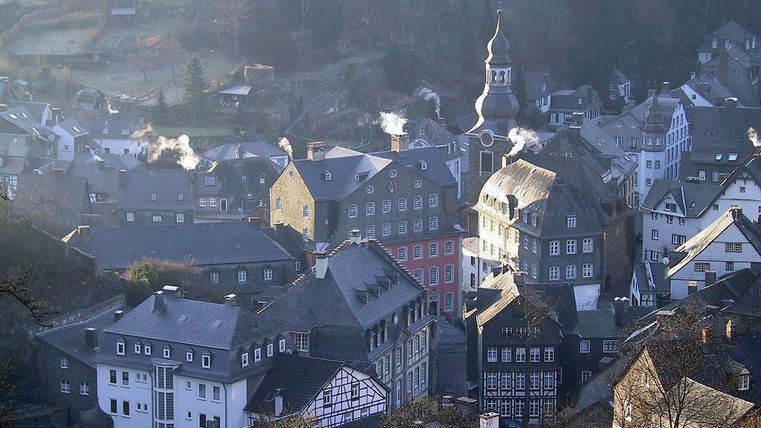 A picturesque town with historic buildings and narrow alleys. The smoke from the chimneys suggests a cozy atmosphere.