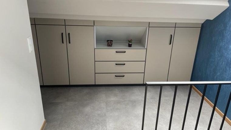 Een moderne ruimte met een heldere kleur en een praktisch kastontwerp. De muren zijn deels wit en deels in een aangename blauwtint geschilderd.
