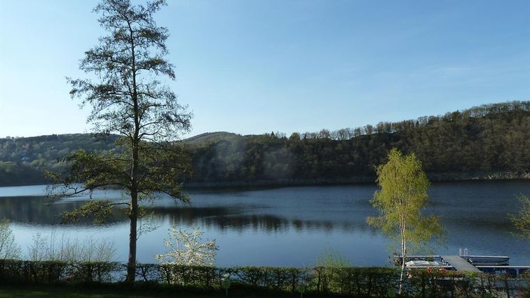 A quiet lake surrounded by trees and gentle hills. The landscape is peaceful and inviting.