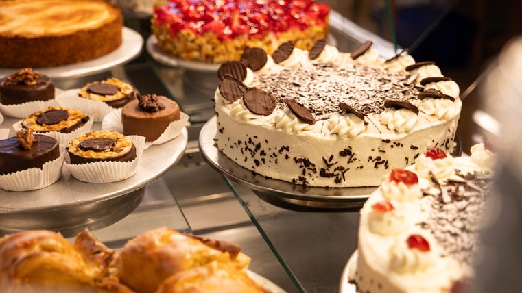 A selection of delicious cakes and pastries. Especially highlighted is a cream cake with chocolate chunks and cherries.