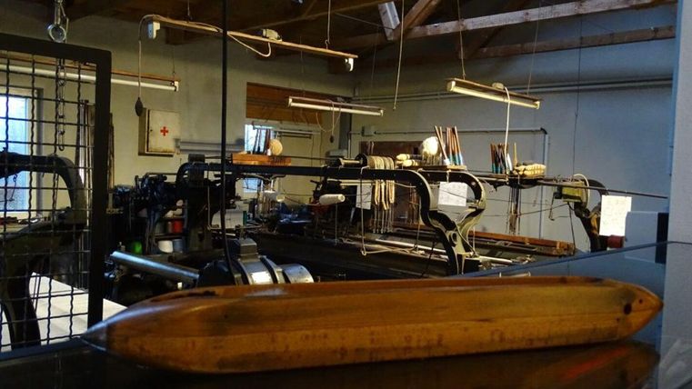 An old workshop with machines and tools. In the foreground lies a wooden object.