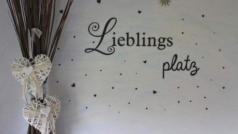 A decorative wall area with the inscription "Favorite Spot". Next to the wall, there are two heart-shaped decorations and some branches.