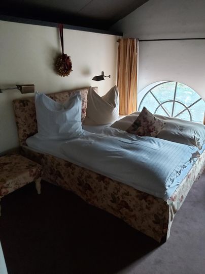 A cozy bedroom with a large bed and a beautiful window. The walls are in neutral colors with decorative curtains.