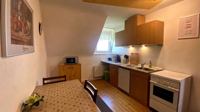 Een gezellige kitchenette met houten kasten en een eettafel. De keuken is licht en goed uitgerust met moderne apparaten.