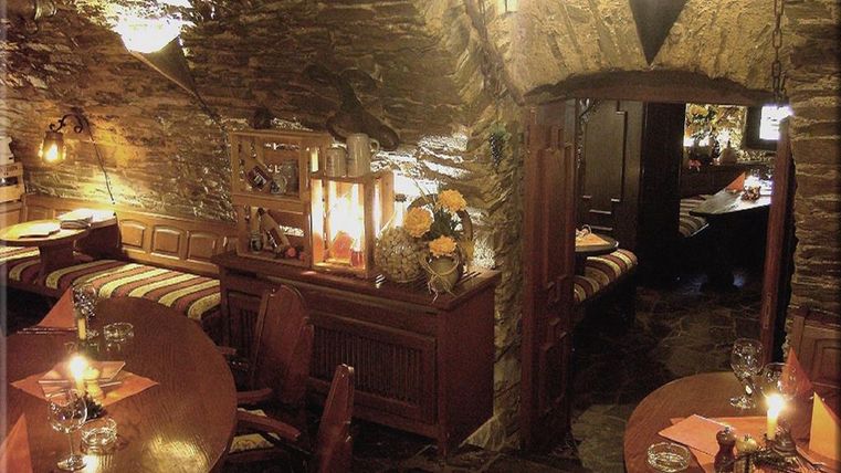Ein gemütliches Restaurant mit Steinwänden und warmem Licht. Tische mit Kerzen schaffen eine einladende Atmosphäre.