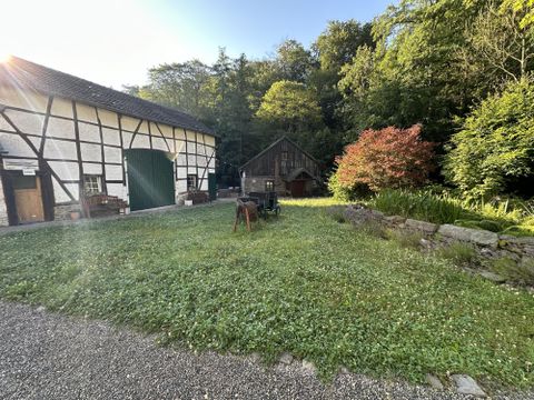 Een idyllische boerderij met een oud vakwerkhuis en een gezellige schuur. De groene tuin is omringd door bomen en bloemen.