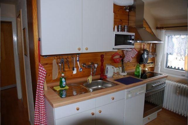 Een gezellige keuken met houten bekleding en moderne apparaten. De ruimte is opgeruimd en goed uitgerust.