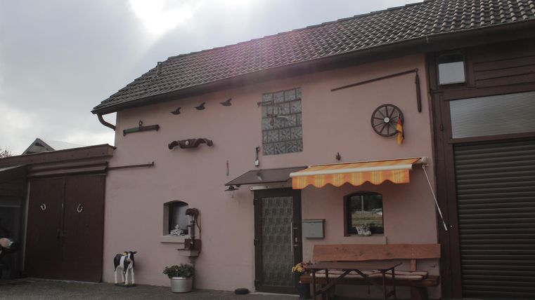 Ein charmantes, pinkfarbenes Haus mit einem gemütlichen Außenbereich. Es hat eine Fensterbank und eine Markise, die zum Sitzen einlädt.