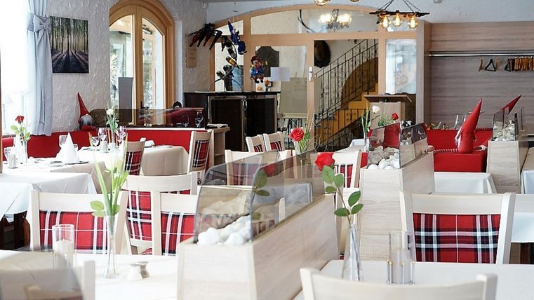 Ein elegantes Restaurant mit weißen Tischtüchern und roten Akzenten. Die Einrichtung ist modern und einladend, ideal für ein angenehmes Essen.