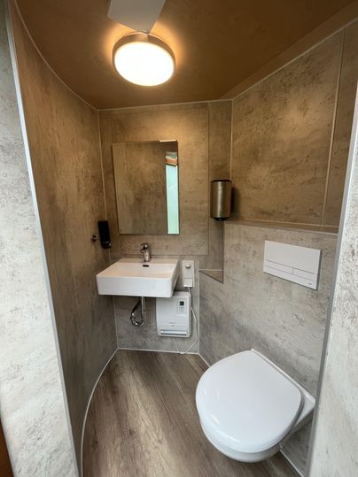 Een moderne badkamer met een toilet en een wastafel. De muren zijn in neutrale kleuren gehouden en de ruimte is goed verlicht.