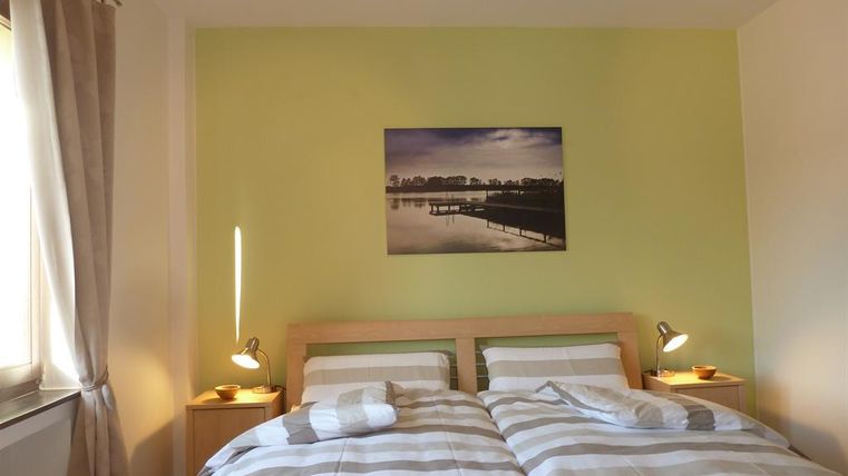 A cozy bedroom with two beds and striped bed covers. On the wall hangs a picture of a peaceful landscape.