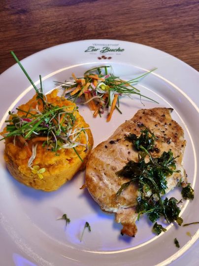 A plate with grilled chicken breast fillet, served with mashed sweet potatoes and fresh vegetables. The dishes are garnished with herbs and beautifully arranged.