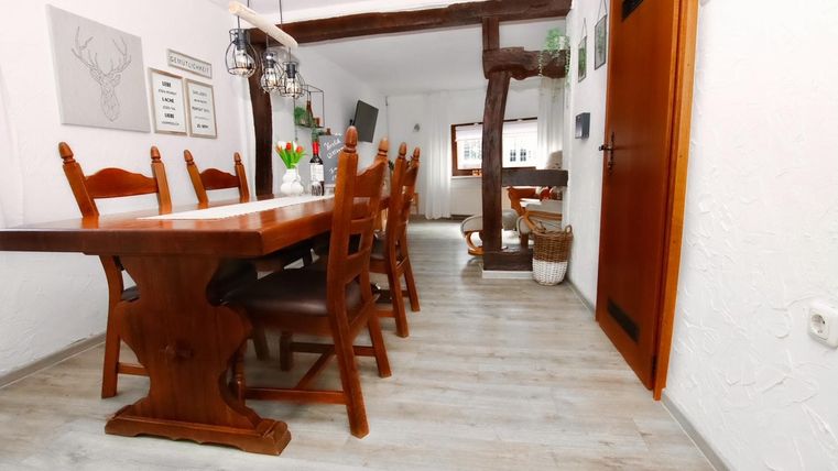 Een uitnodigende eetruimte met een grote houten tafel en stoelen. De ruimte heeft een heldere sfeer met houtdetails en aangename decoratie.
