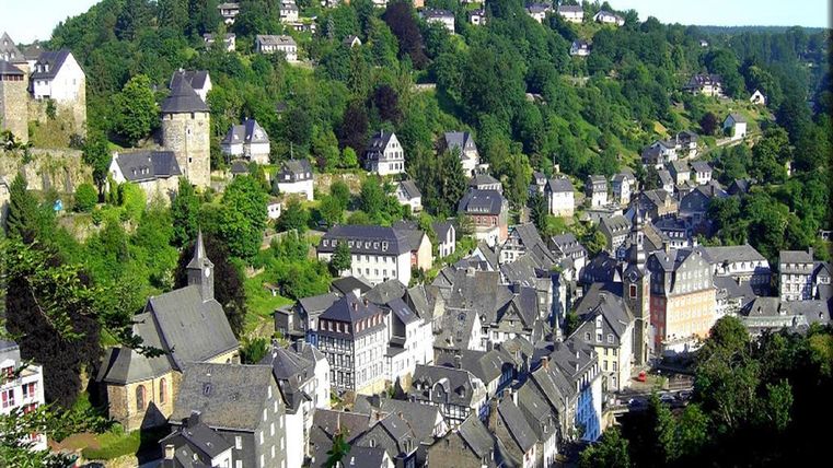 Eine malerische Stadt mit engen Gassen und historischen Gebäuden, umgeben von grünen Hügeln. Die Aussicht zeigt ein charmantes Dorf mit viel Natur.