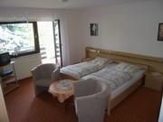 Een gezellig hotelkamer met twee eenpersoonsbedden. Er is een kleine tafel en twee stoelen, evenals een balkon met uitzicht.
