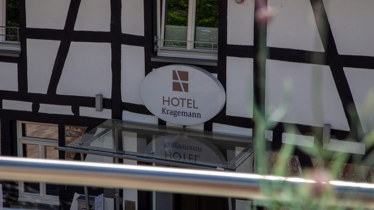 A hotel with a classic half-timbered style and a modern sign. The entrance is clearly visible and inviting.