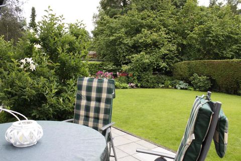 Een gezellige tuin met groen gras en kleurrijke bloemen. Twee stoelen en een tafel nodigen uit om te ontspannen.