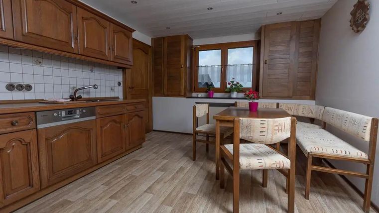 Eine gemütliche Küche mit Holzschränken und einem kleinen Essbereich. Ein Fenster bringt natürliches Licht in den Raum.