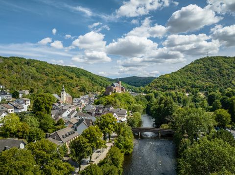 A picturesque valley with a small town by the river. Green hills surround the gentle landscape under a clear sky.