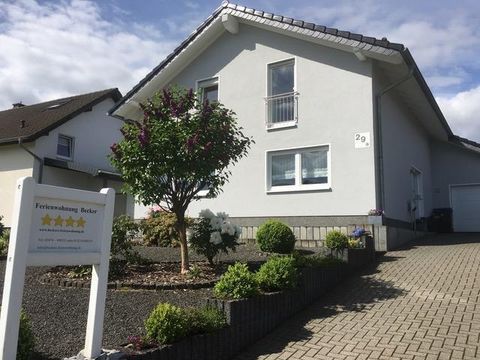 Een gezellig vakantiehuis met een onderhouden tuinlandschap. De ingang is gemarkeerd met een bord dat de accommodatie adverteert.