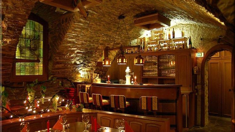 Ein gemütliches Restaurant im Untergeschoss mit einem Holztheke und warmem Licht. Die Tische sind elegant gedeckt und schaffen eine einladende Atmosphäre.