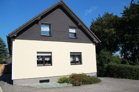 A modern house with a two-toned exterior and a well-kept garden. The sky is clear and the surroundings are quiet.