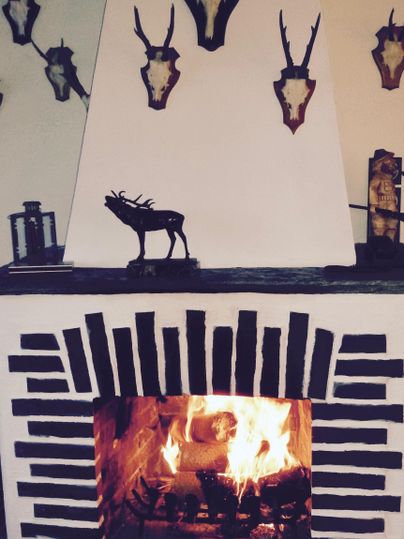 Ein Kamin mit loderndem Feuer und einem Dekor aus Tierkopf-Trophäen. Die Wände sind rustikal und schaffen eine gemütliche Atmosphäre.