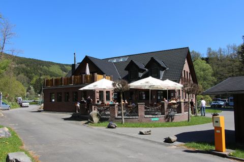 A charming restaurant with a terrace and sun umbrellas. It is located in a quiet setting, surrounded by trees.