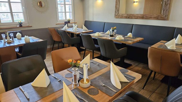 A cozy restaurant with elegant tables and chairs. The tables are lovingly set and create an inviting atmosphere.