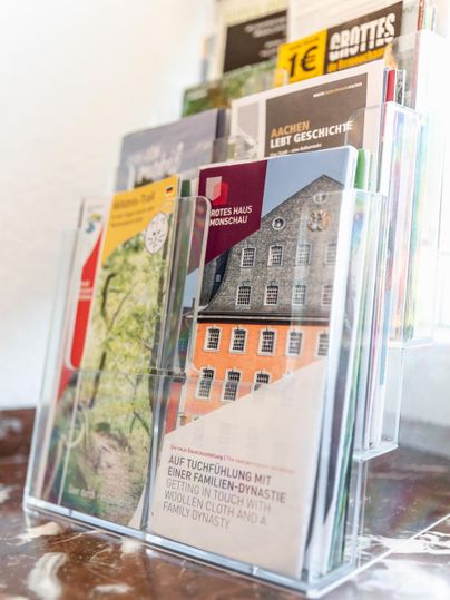 Een flyerhouder met verschillende brochures over lokale bezienswaardigheden en geschie densthema's. De brochures zijn kleurrijk en informatief vormgegeven.