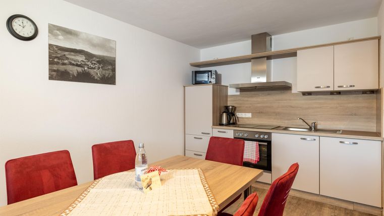 Een moderne keuken met een eetgedeelte. Rode stoelen en lichte meubels creëren een uitnodigende sfeer.
