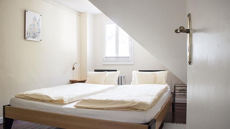 Een gezellige slaapkamer met een tweepersoonsbed en twee kussens. Een raam zorgt voor veel daglicht.