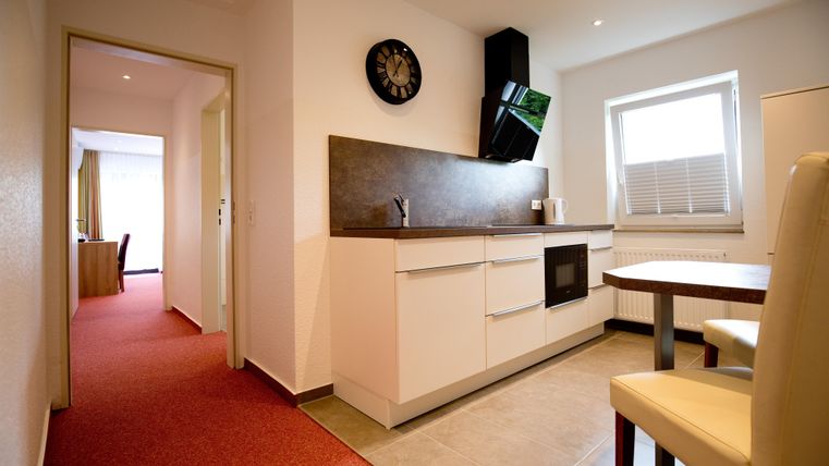 A modern kitchen with bright walls and a large window. The space is well-lit and provides easy access to an adjacent room.