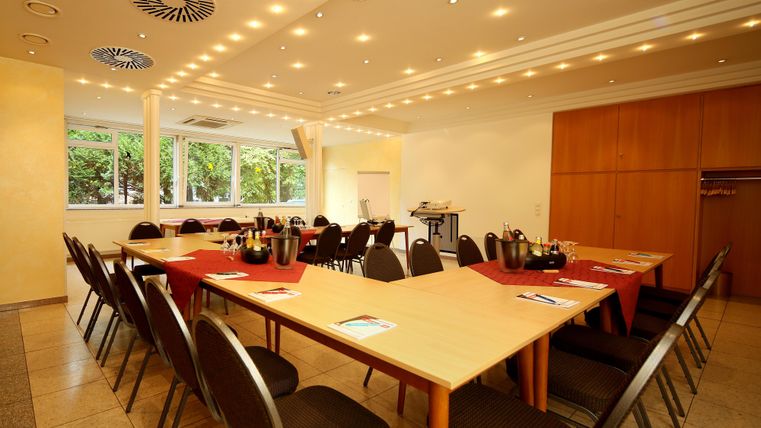 An elegant conference room with a large table and several chairs. The room is well-lit and has windows that provide natural light.