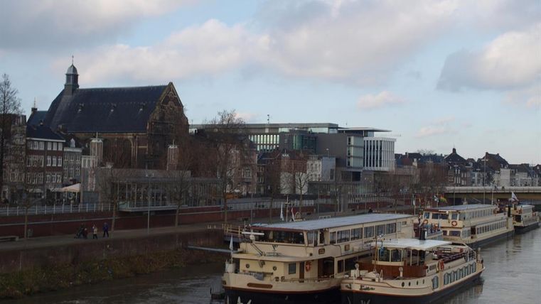 Een uitzicht op het water met meerdere boten op de voorgrond. Op de achtergrond zijn gebouwen en een kerk te zien, onder een bewolkte lucht.