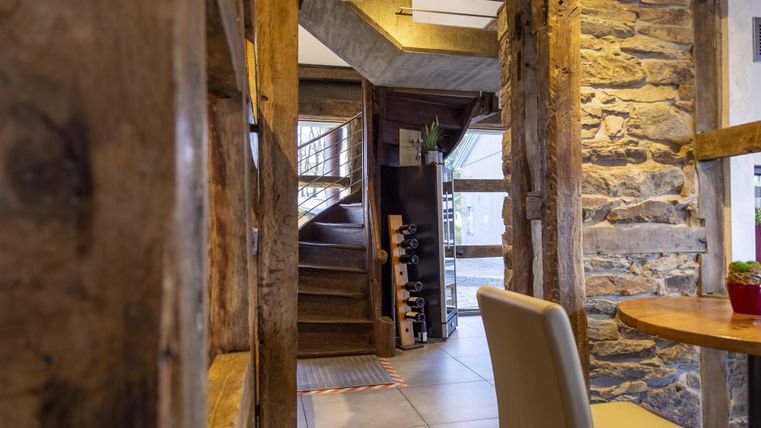 A cozy interior with rustic wooden walls and a staircase. On a table, there is a small plant.