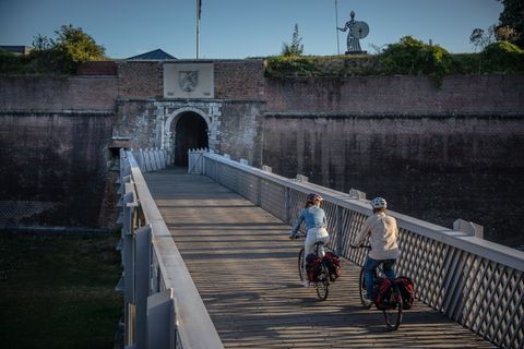 Zwei Radfahrer fahren auf einer Brücke aus Holz vor der Zitadelle Jülich