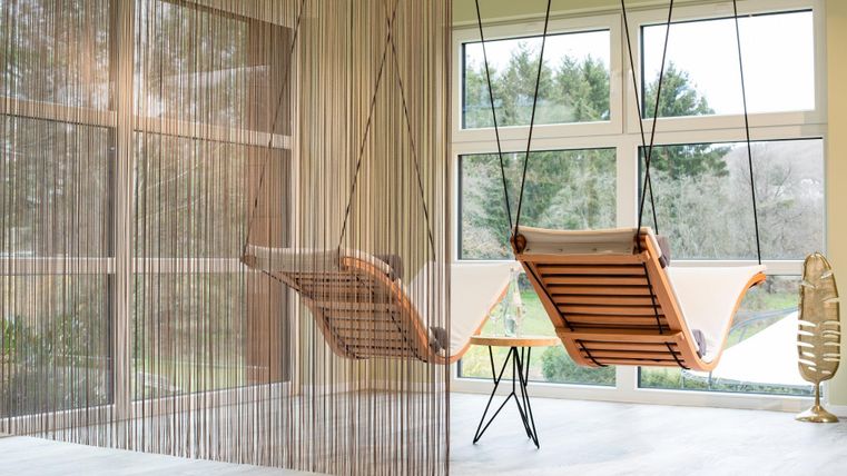 Een rustige kamer met twee schommelstoelen. Grote ramen bieden uitzicht op de natuur buiten.