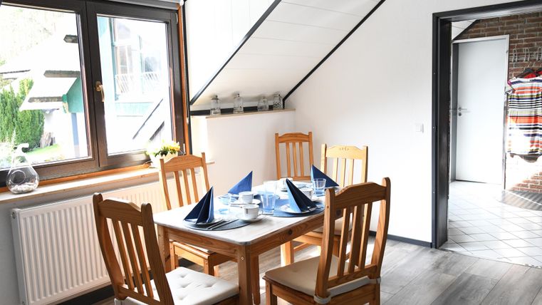 A bright dining room with a table and four chairs. The table is festively set with blue napkins and dishes.