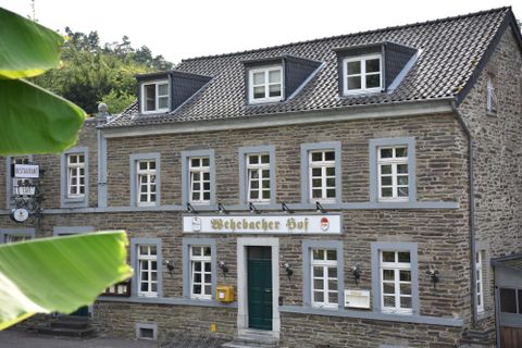 Ein hübsches, traditionelles Gebäude mit grauer Fassade und vielen Fenstern. Das Schild "Weilbacher Hof" ist gut sichtbar.