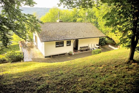 Ein gemütliches Haus inmitten von Bäumen. Es liegt auf einem sanften Hügel und ist von grünen Wiesen umgeben.